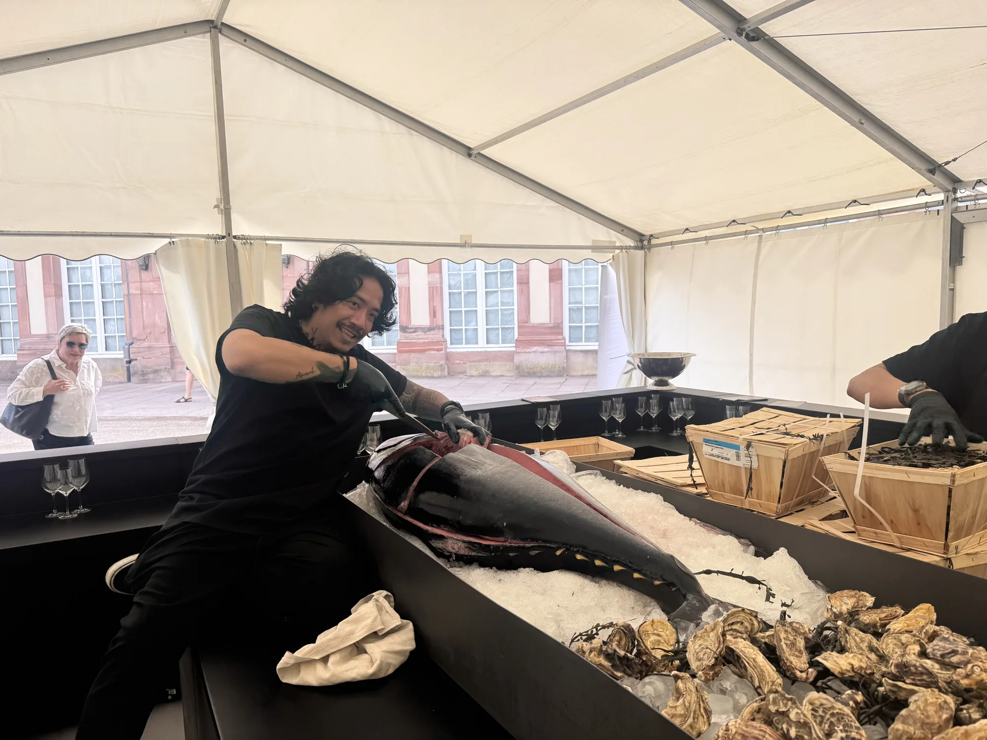 Der Sushi-Meister zerlegt den Bluefin Tuna im Zelt, dahinter die Fassade des Schlosses Schwetzingen